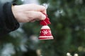 Red bell in a manÃ¢â¬â¢s hand on the background of a Christmas tree. Christmas decoration. New year is coming.